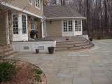 A Landscape Architect designed this large stonework patio which surrounds an elevated outdoor deck.